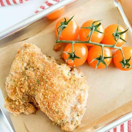 Crispy chicken and cherry tomatoes on a small sheet pan.