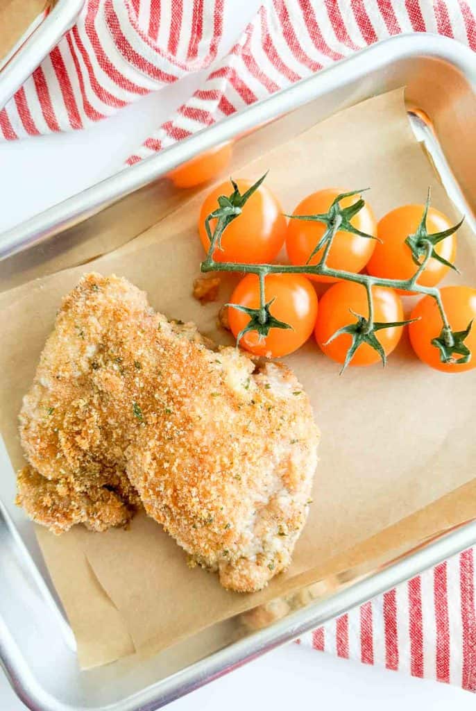 Crispy chicken and cherry tomatoes on a small sheet pan.