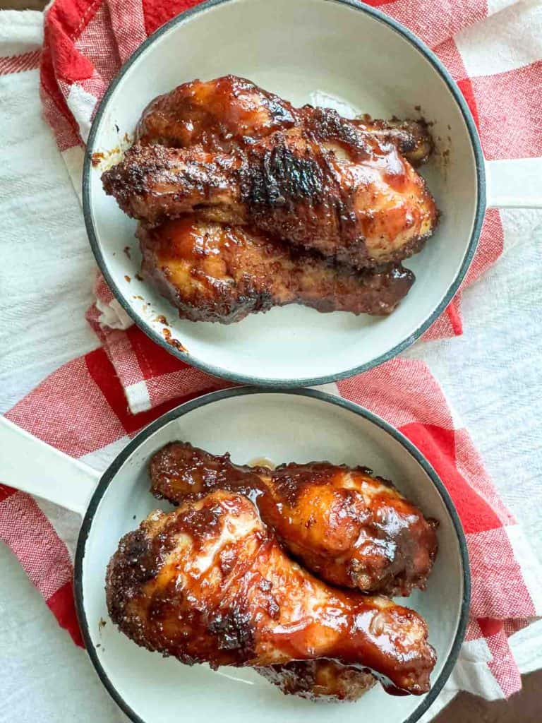 BBQ chicken legs in white pans.