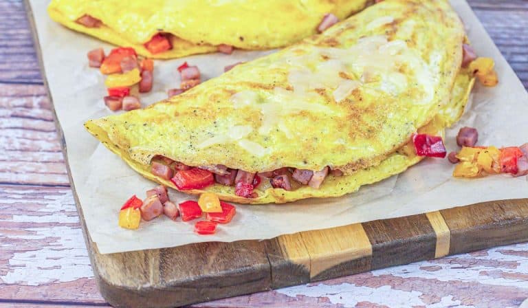 A Denver omelet with a golden exterior is presented open-faced, revealing a hearty filling of diced ham and colorful bell peppers.