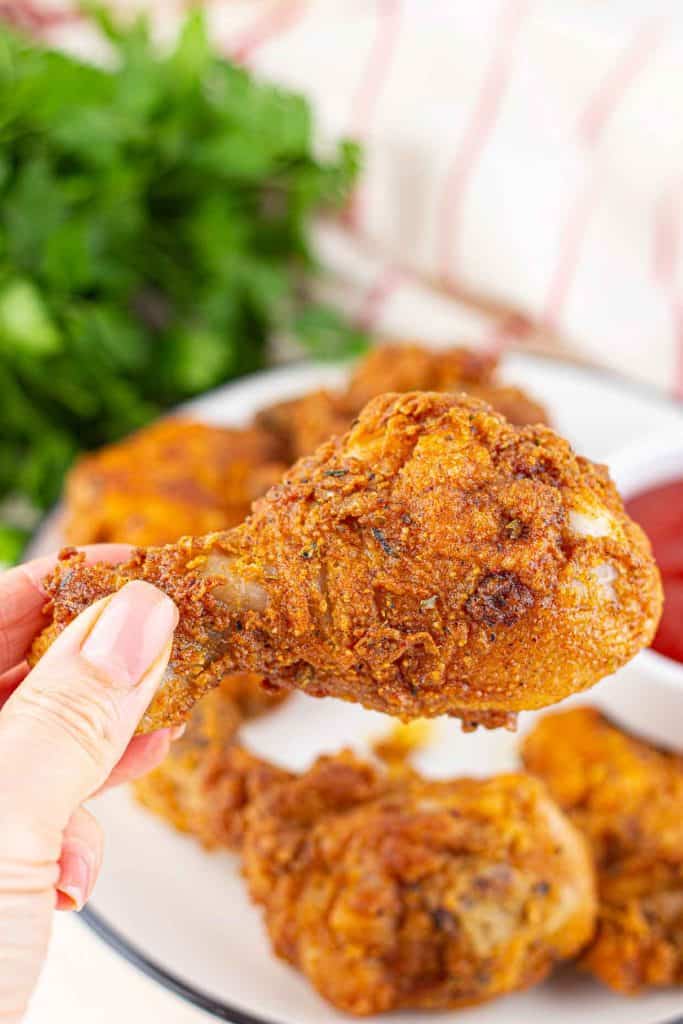 A hand holding fried chicken.