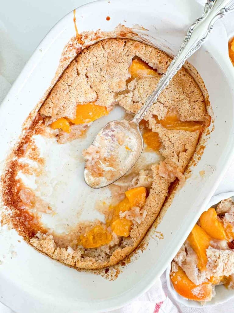 An dish of spiced peach cobbler with most of it scooped out. 