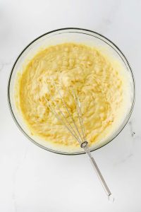 Mixed pudding mixture in a bowl with a whisk on it.
