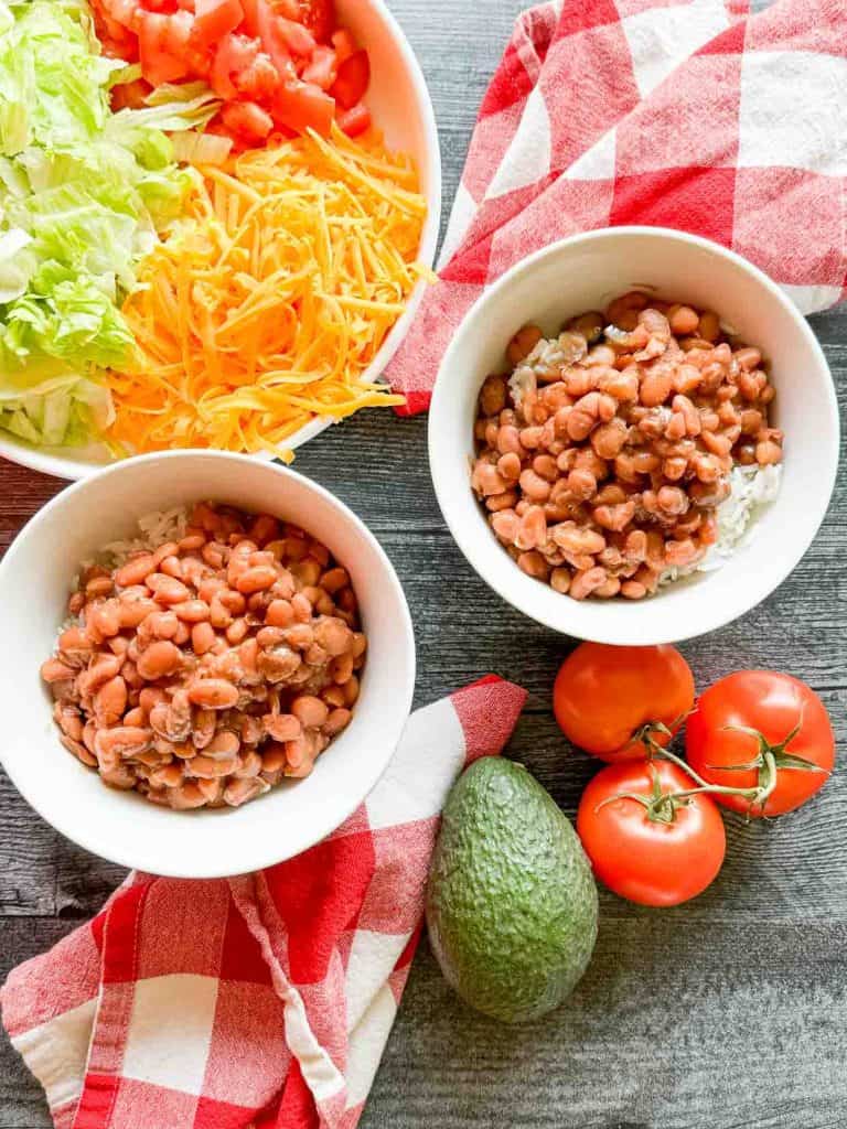 Beans over rice in bowls with toppings. 