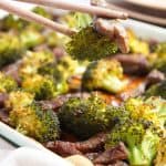 Chopsticks holding beef and broccoli.