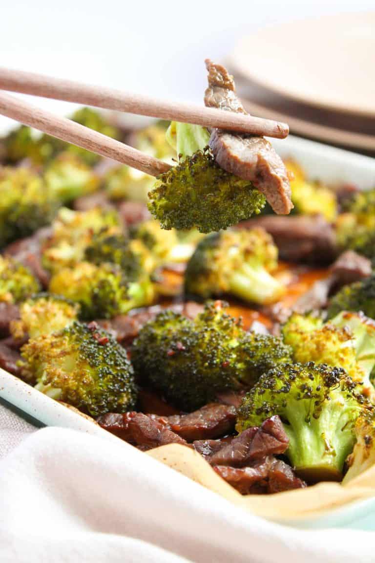 Chopsticks holding beef and broccoli.