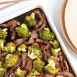 Sheet pan beef and broccoli with plates and chopsticks.