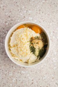 Ricotta, eggs, cheeses, and seasonings in a bowl for 3 Cheese Manicotti filling.