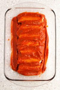 Filled 3 Cheese Manicotti covered with sauce in a baking dish.