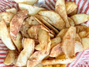 Apple slices mixed with sugar and cinnamon, evenly coated.