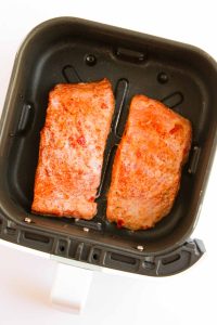 Salmon fillets placed in an air fryer basket.