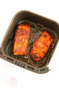 Cooked salmon fillets with a crispy, caramelized coating in the air fryer basket.