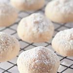 Cream cheese cookies cooling on a wire rack, dusted with powdered sugar.