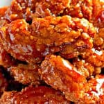 Sweet and spicy chicken fingers served on a white platter.