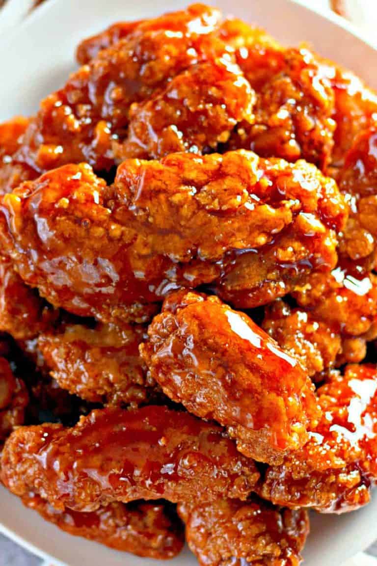 Sweet and spicy chicken fingers served on a white platter.