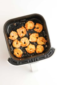 Crispy, golden-brown shrimp in the air fryer basket.