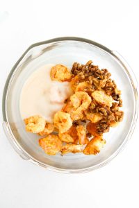 Bowl with crispy shrimp, candied walnuts, and sauce before mixing.