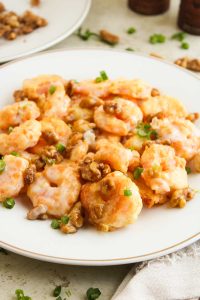 Side view of honey walnut shrimp on a white plate.