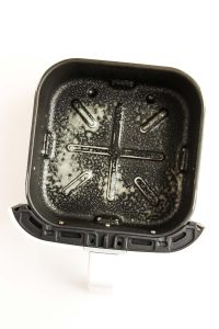 Air fryer basket sprayed with oil.