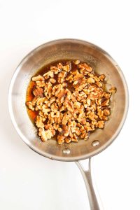 Walnuts added to the honey glaze in the pan.