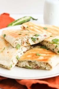 Crispy jalape&ntilde;o popper chicken quesadillas on a plate with cilantro.
