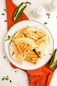 Overhead shot of quesadillas with fresh jalape&ntilde;os and cilantro.