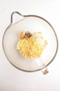 Mozzarella, mayonnaise, and seasonings in a glass mixing bowl.