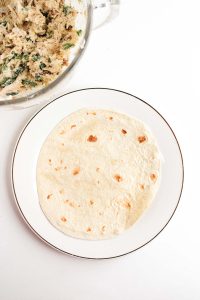 A tortilla on a plate next to the mixing bowl.