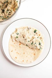 Half of the tortilla topped with the chicken mixture.