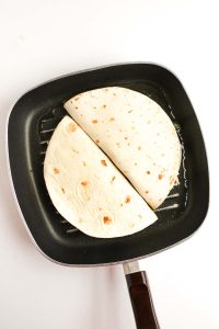 Two quesadillas cooking in a grill pan.