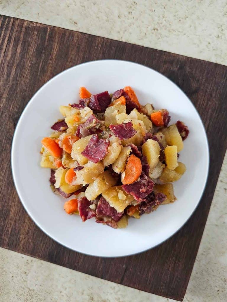 A plate of corned beef hash with potatoes and carrots.