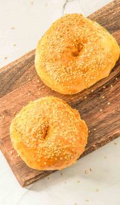 Two Easy Air Fryer Bagels with sesame seeds on a wooden board.