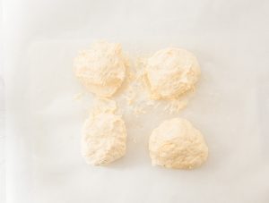 Four dough portions on parchment paper for Easy Air Fryer Bagels.