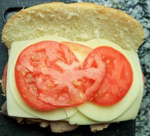 Fresh tomato slices added on top of the cheese in the sandwich.