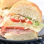 Halved Italian grinder sandwich showing layers of meat, cheese, tomato, and lettuce.