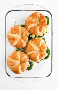 Assembled croissant breakfast sandwich in baking dish.