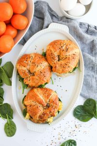 Top view of croissant breakfast sandwich with spinach and oranges.