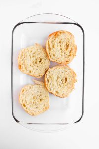 Halved croissants in baking dish.