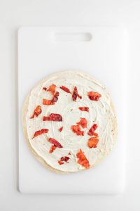 Crushed bacon is added on top of the tortilla with the cream cheese mixture.