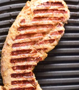 Pork tenderloin with grill marks cooking on a grill pan.