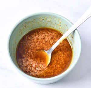 Bowl of marinade for grilled pork tenderloin with a spoon resting inside.