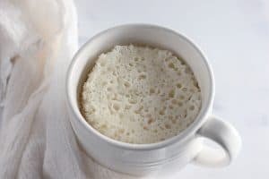 White mug with cooked plain white mug cake.