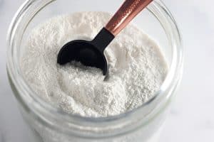 Glass jar of white mug cake mix with a measuring spoon.