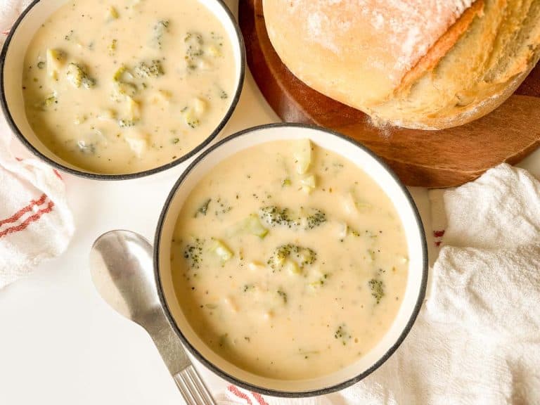 Overhead of two bowls of broccoli cheese soup with bread.