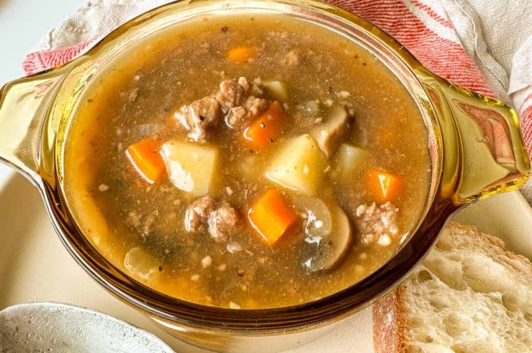 Top-down view of beef stew with vegetables in a clear bowl.
