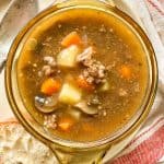 Top-down view of beef stew with vegetables in a clear bowl.
