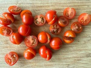 Halved cherry tomatoes on a cutting board.