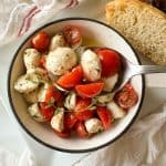 Spoonful of salad held over the bowl with bread beside it.