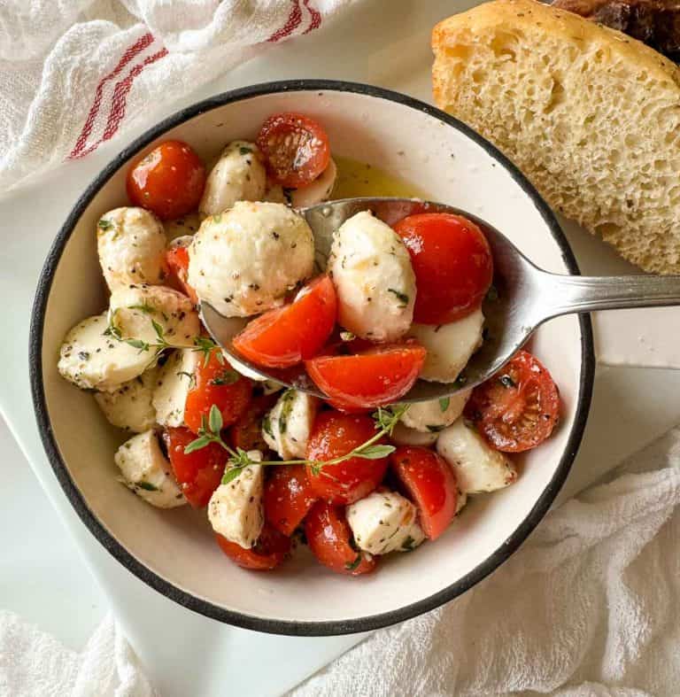 Spoonful of salad held over the bowl with bread beside it.