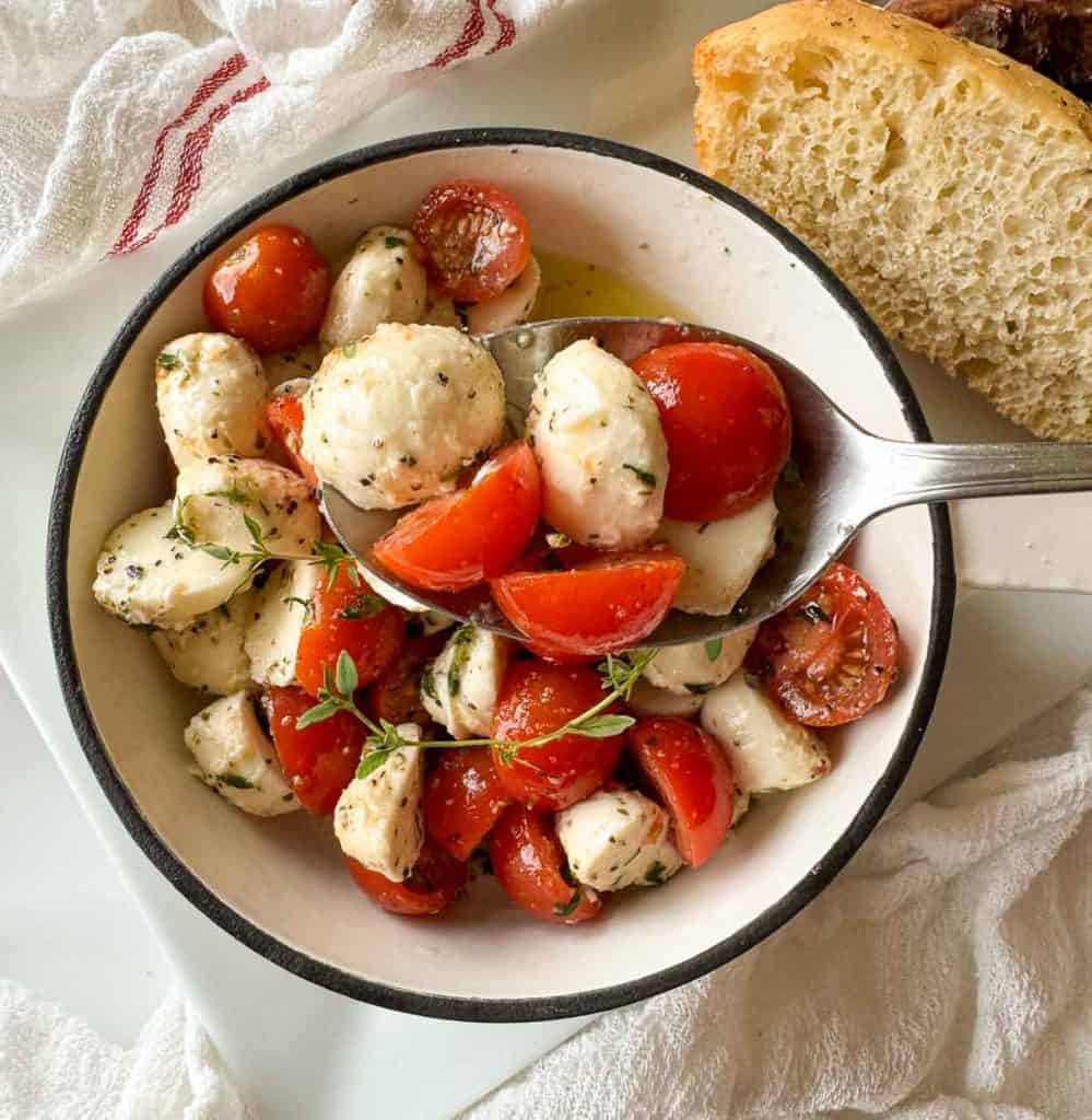 Spoonful of salad held over the bowl with bread beside it.